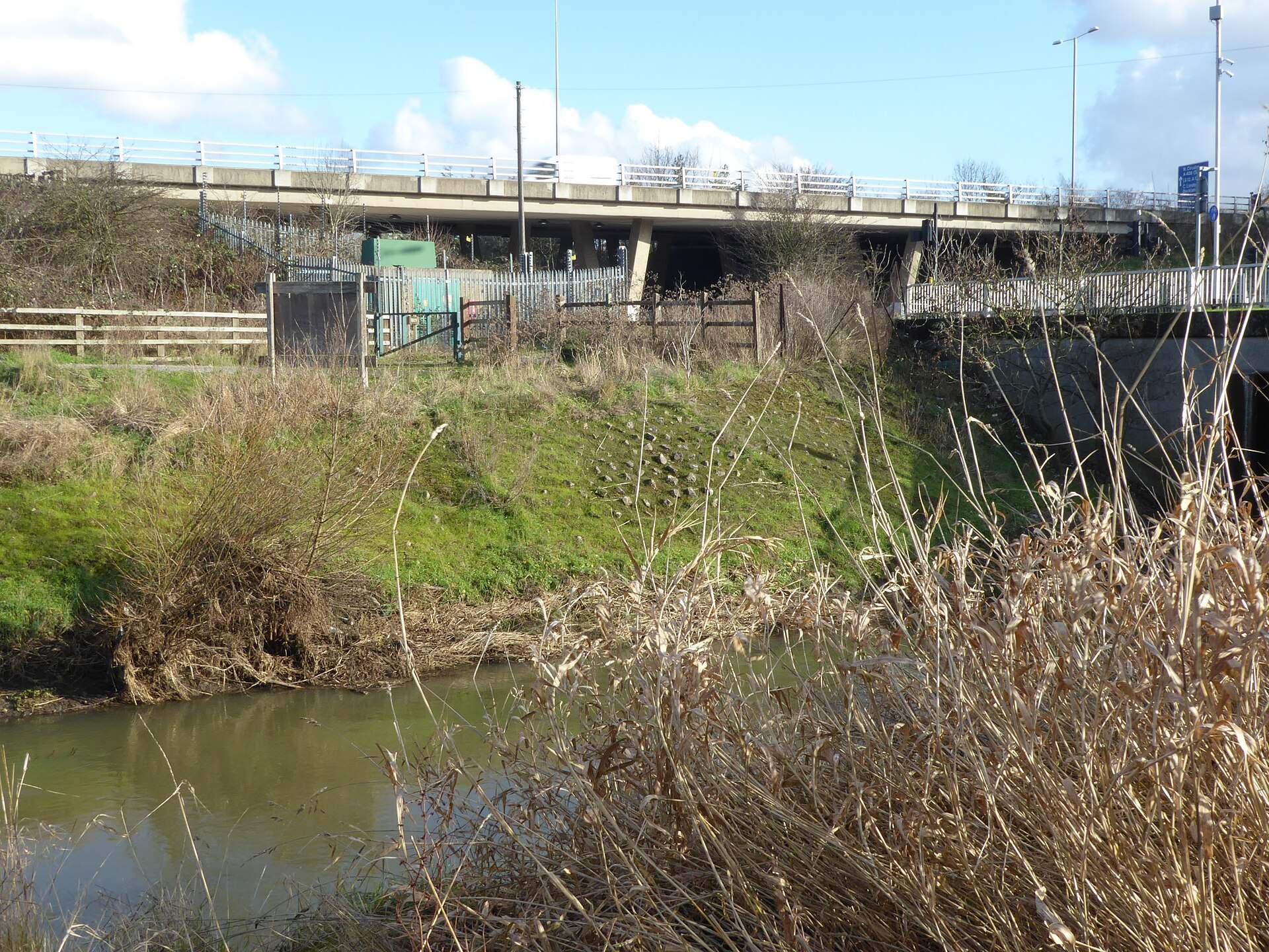 The River Roding with the M11 motorway viaduct behind it, Roding Valley Park near Chigwell
